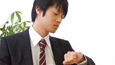 待ち合わせで時計をみてるスーツの男性